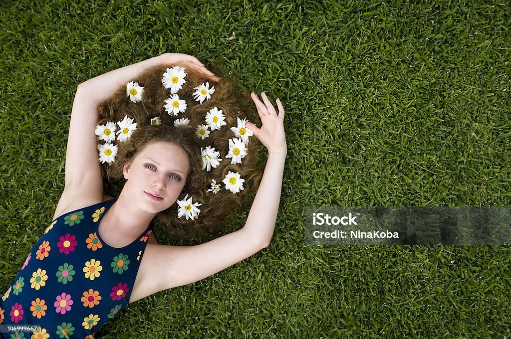 Blonde teen lying on the grass Blonde teen with green eyes and wearing a blue dress decorated with flowers lying on the grass 14-15 Years Stock Photo