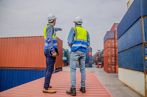 Team Engineers are inspecting the transportation of cargo with containers inside the warehouse. Container in export and import business and logistics.
