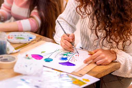 Painting Workshop. Women paints picture on canvas with watercolor paints in her studio