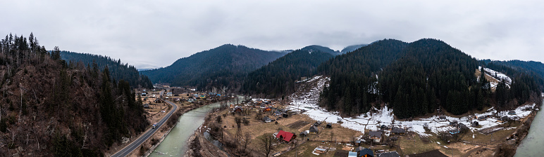 Viaduct railway bridge in the Carpathians of Ukraine, a view of the bridge from a height, a winter panorama of a village in the mountains.