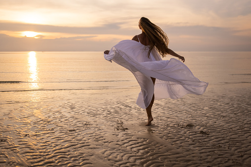 Beautiful brunette girl holding her hair up and sitting on the sandy beach