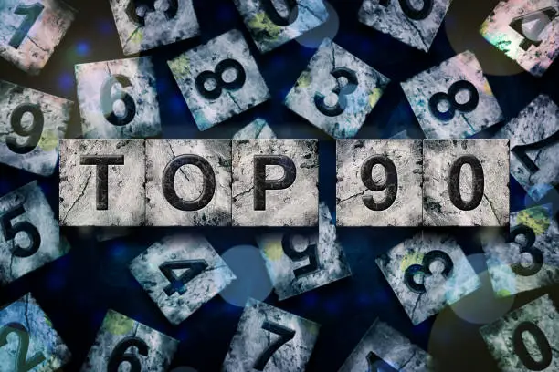 Photo of Top 90, words, above different numbers, on a dark blue background, with different letters. Alphabet on stone blocks.Rating. Rating concept.