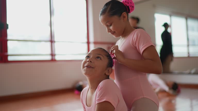 Ballet dancer fixing hair for classmate at a dance studio