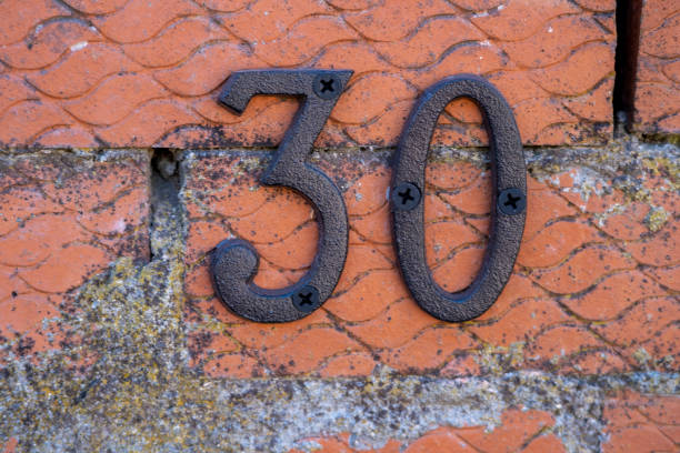 istock Number 30, thirty, in rusty metal on a brick wall . 1470004680