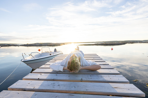 Woman contemplates reflection on the lake at sunset