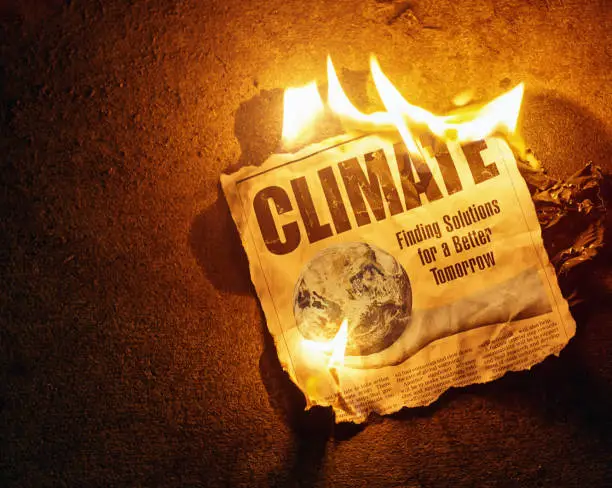 Photo of Burning newspaper headline saying CLIMATE with text global warming, renewables and other technologies