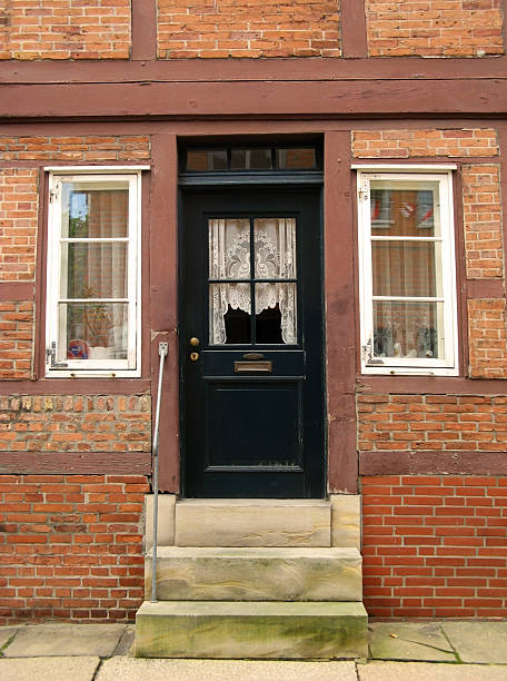 The dark green door of an old timber frame house.