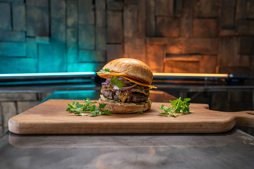 Tasty cheeseburger on a wooden plate.