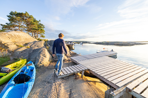 He walks on a wooden pier with a positive relaxed attitude