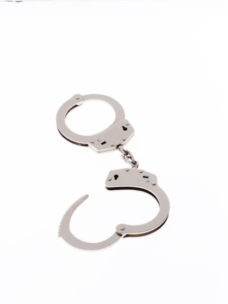 Metal handcuffs with one half open on a white surface