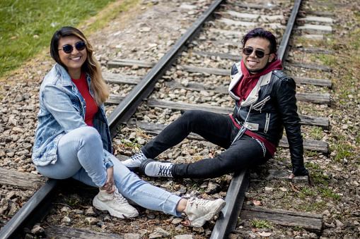 Portrait of a young couple sitting on the train track outdoors