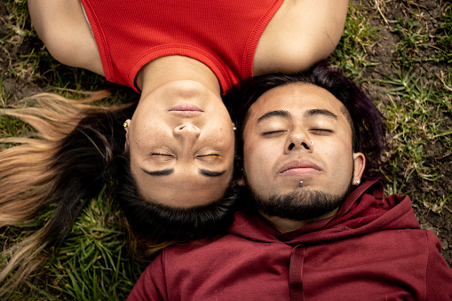 Young couple relaxing lying on grass outdoors