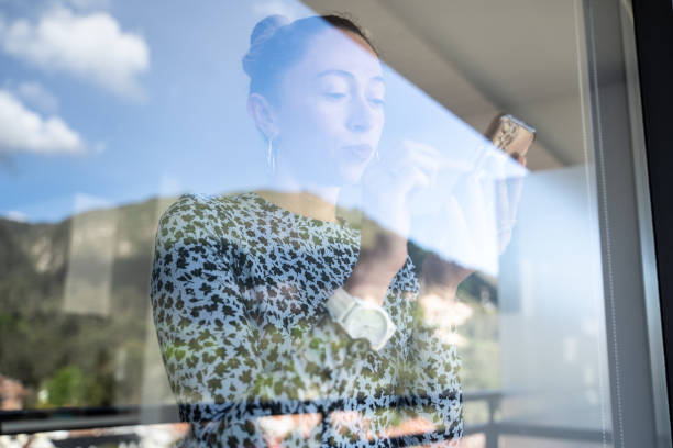 istock Mid adult woman using a mobile phone at home - view through window 1470011738