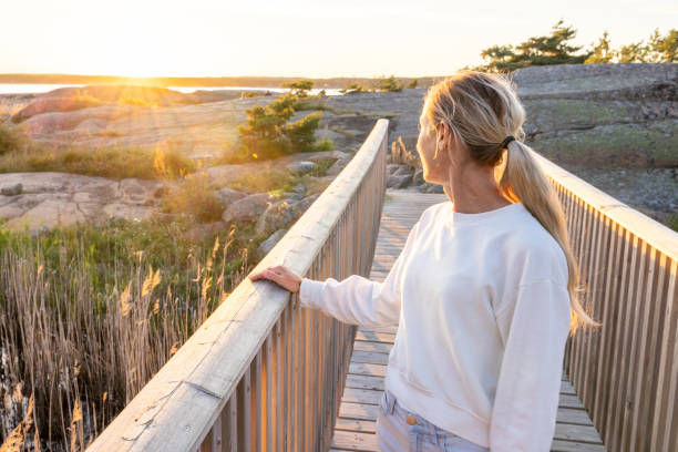 Woman contemplates the sunset from a wooden bridge, sunset time stock photo