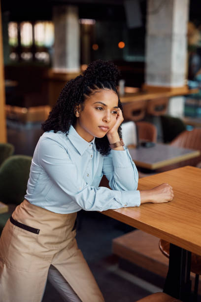 istock Young black waitress thinking of something while working in a cafe and looking away. 1470018235