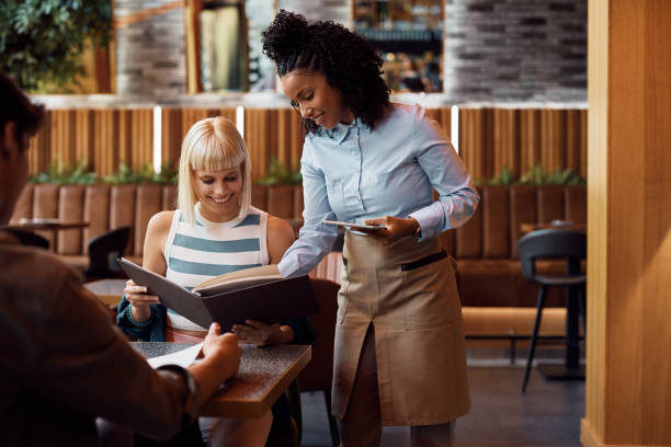 istock Happy waitress assisting her customer with choosing the order from a menu. 1470018322