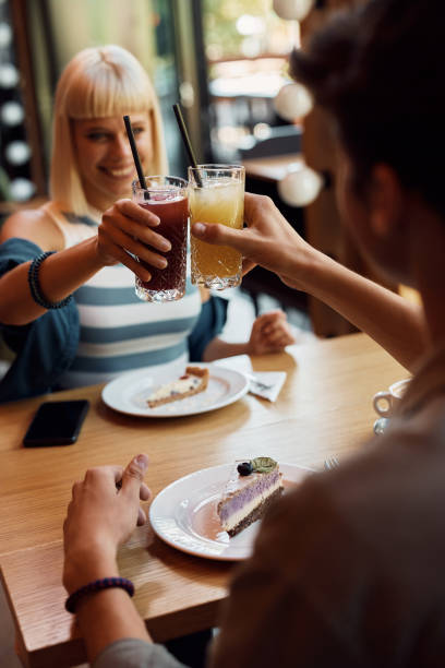 istock Close up of couple toasting while drinking juice in a cafe. 1470018428