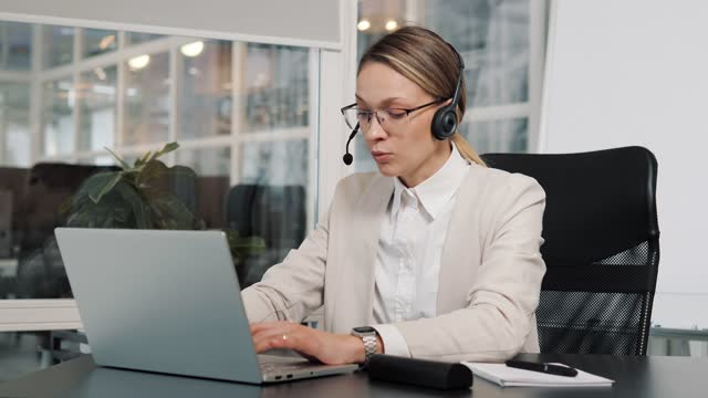 Top managerexecutive wears headset video calling on laptop. Businesswoman webinar speaker streaming live web training. Call center agent, service support lady speaking to distance customer in webcam.