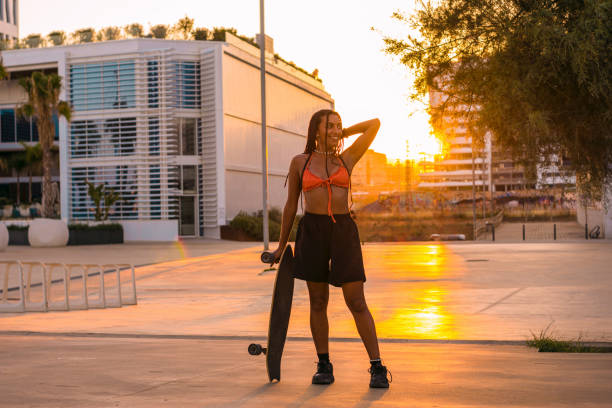 istock Brown-skinned woman posing with her skateboard on the seafront at summer sunset. 1470021121