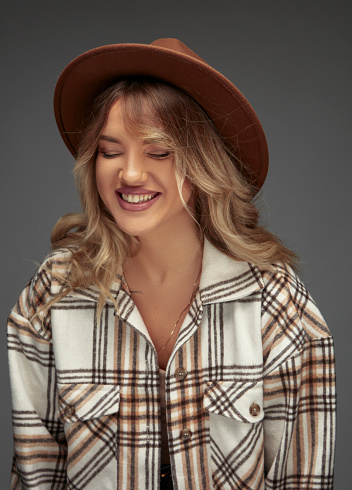 Portrait of beautiful blonde woman in a plaid shirt, wearing a fedora. The beautiful woman had a fit of laughter.