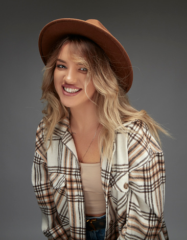 Portrait of beautiful blonde woman in a plaid shirt, wearing a fedora.