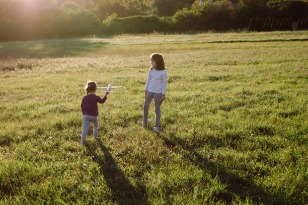 istock Two sisters running on the meadow while plying whit toy plane during spring day 1470022829