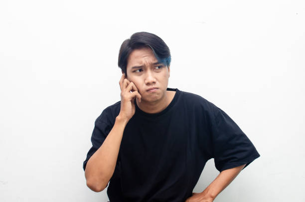 istock Thoughtful asian man thinking and wondering with hand touching skin as thinking gesture isolated over red background. 1470024735
