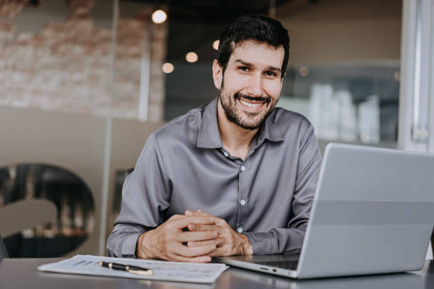 istock Business man looking at camera beside laptop 1470025069