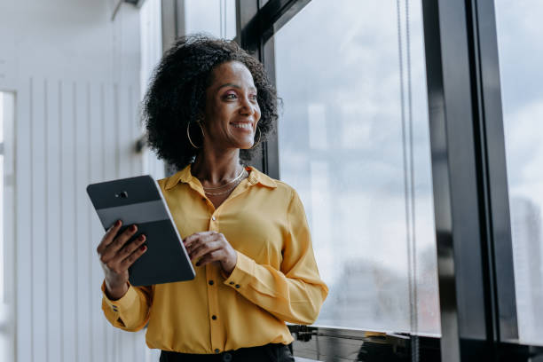istock A businesswoman holding digital tablet looking at window view smiling 1470025370
