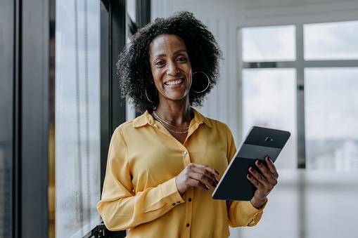 Portrait of businesswoman holding tablet and looking at camera smiling