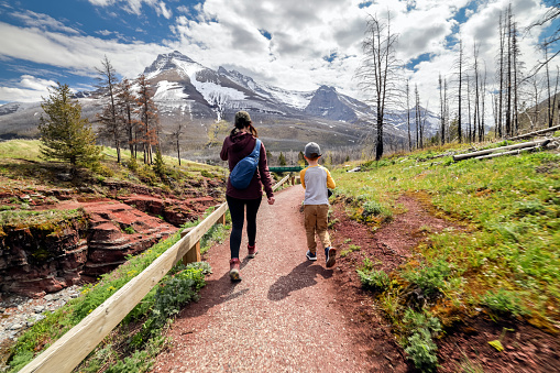 Mother and Son Hiking In Waterton Lakes National Park, Alberta, Canada on a sunny day of summer. They are visiting the Red Rock Canyon.