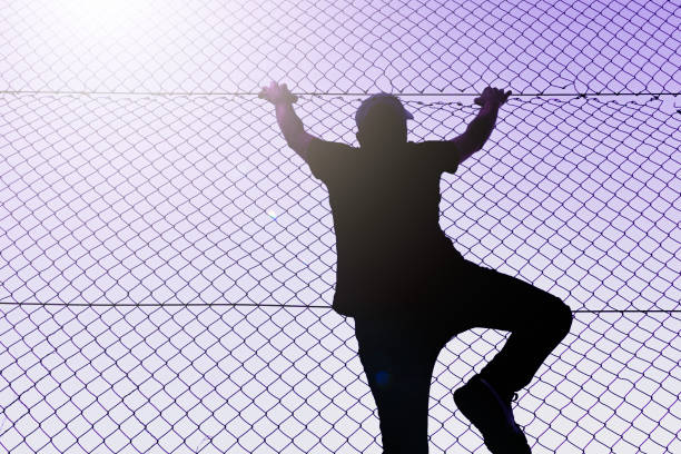 istock man climbing the metal fence 1470030538