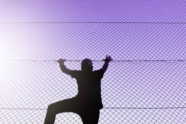 istock man climbing the metal fence 1470030540