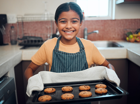 Girl kid, cookies and baking with portrait and bakery skill, learning and development with success and pride. Cookie, dessert and proud child baker cooking in kitchen with achievement and happiness.