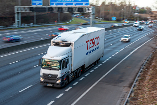 Chorleywood, UK - February 25, 2023: Lorry belonging to Tesco, largest British multinational groceries and general merchandise retailer blured in motion on British motorway M25.