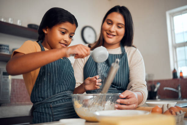 istock Help, learning and cooking food with mother in kitchen for lesson, independence and bonding moment. Focus, teaching and mom helping child with baker recipe at happy family home in Mexico. 1470030996