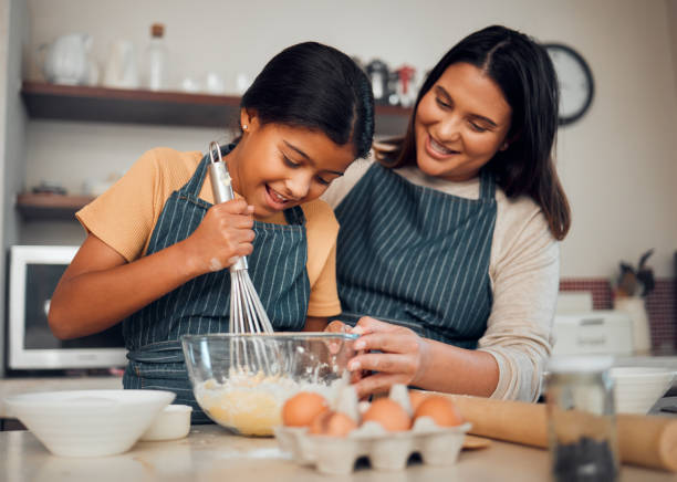 istock Bakery, baking and woman with girl learning to bake, cooking skill and development with happiness and help. Mother, child with fun activity and teaching to learn with food ingredients in family home. 1470031002