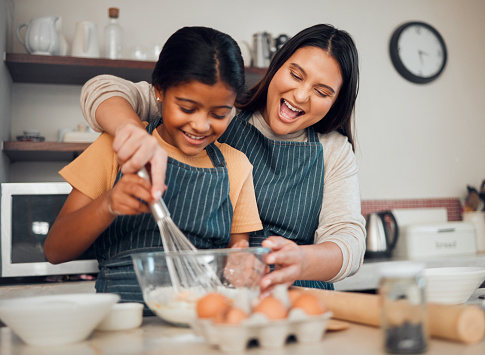 Mom, kid and baking in kitchen, family home and house for childhood fun, learning or development. Mother and daughter cooking, teaching and mixing ingredients in bowl to bake dessert, flour and whisk