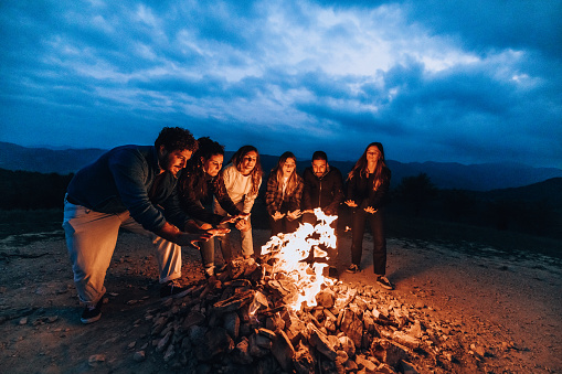 Friends celebrating and having fun around a bonfire.