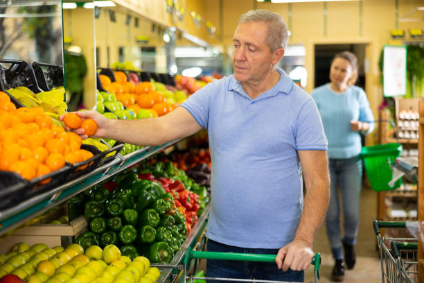 istock Elderly man purchaser taking fresh tangerines in grocery store 1470033042
