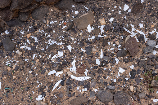 Soil full of stones and rocks and broken pieces of porcelain, enlighted by the sunlight. Hondura, Fuerteventura, Canary Islands, Spain.