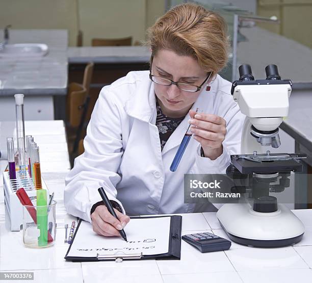 Female Scientist Holding Test Tube And Taking Notes Stock Photo - Download Image Now