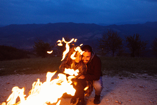 Couple enjoy a bonfire in mountain.