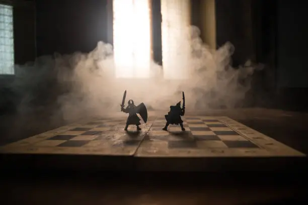 Photo of Medieval battle scene with cavalry and infantry on chessboard. Chess board game concept of business ideas and competition and strategy ideas Chess figures on a dark background with smoke and fog.