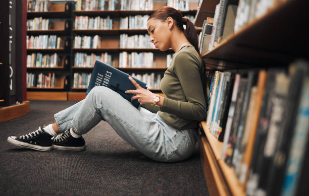 istock Book, reading and library student on floor with learning, education and research for school, university or college with inspiration. Bookshelf, Bible study history and a woman on ground reading book 1470038797