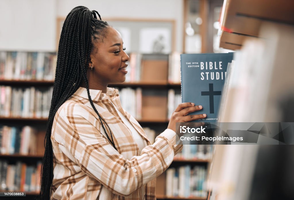 Religion book, education and black woman in a library for research, studying God and knowledge on the bible at college. Learning, smile and African student with decision of books on a scholarship Christianity Stock Photo