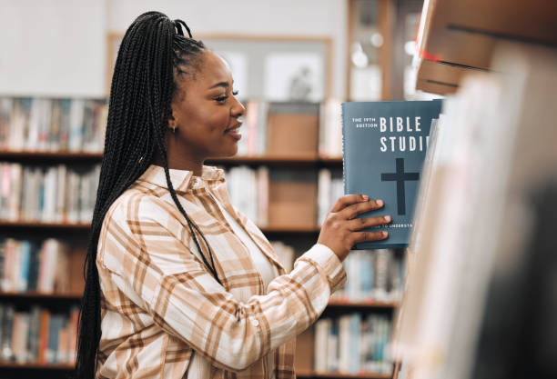 Religion book, education and black woman in a library for research, studying God and knowledge on the bible at college. Learning, smile and African student with decision of books on a scholarship Religion book, education and black woman in a library for research, studying God and knowledge on the bible at college. Learning, smile and African student with decision of books on a scholarship bookstore stock pictures, royalty-free photos & images