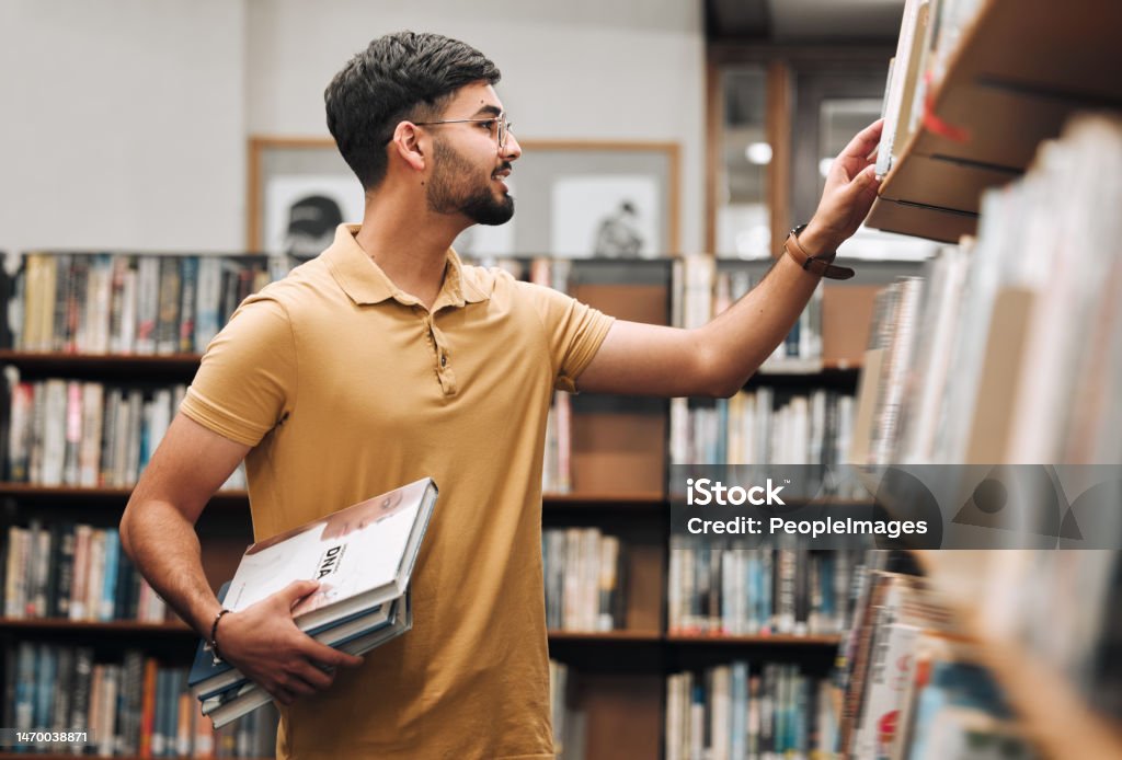 Student man, search bookshelf and library for reading, information and knowledge at university. College student, research and studying for education, college and learning for scholarship in Marseille Library Stock Photo