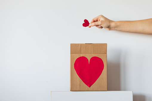 a gift with a heart on a white background and a hand with a heart. A symbol of love. High quality photo