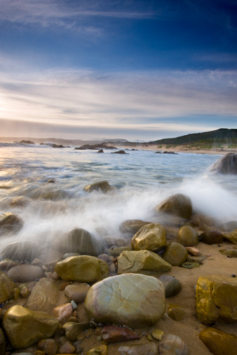 A slow-motion capture of a wave crashing against rocks on a beautiful beach on The Garden Route, South Africa.